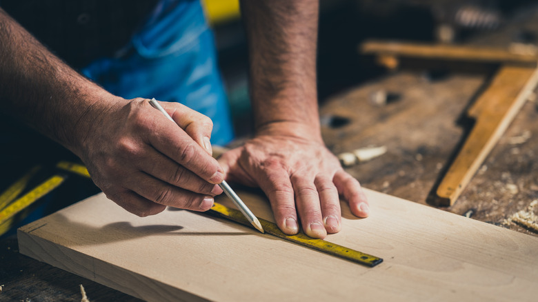 hands marking wood measurements 