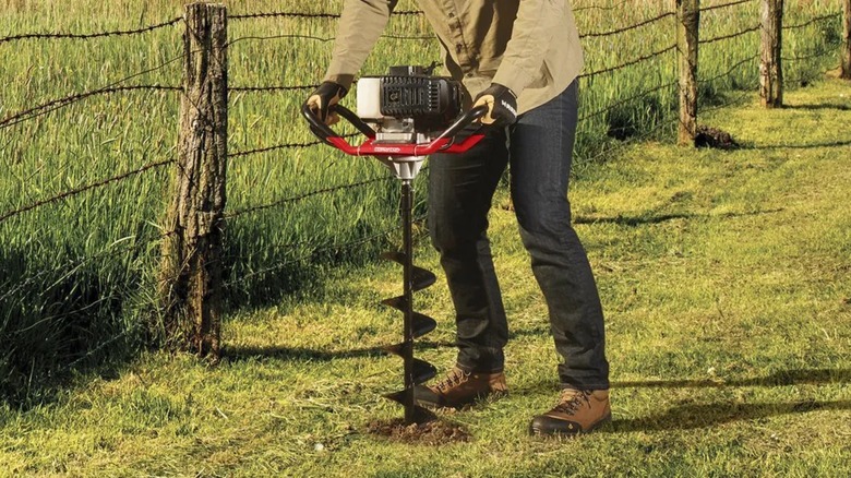 Person creating a hole with a Predator Auger