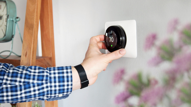 Man adjusts a thermostat in a house