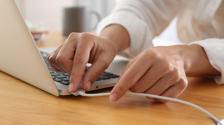 Woman plugging in a laptop.