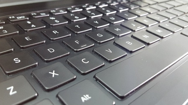 A hand prying a keycap with a small screwdriver.