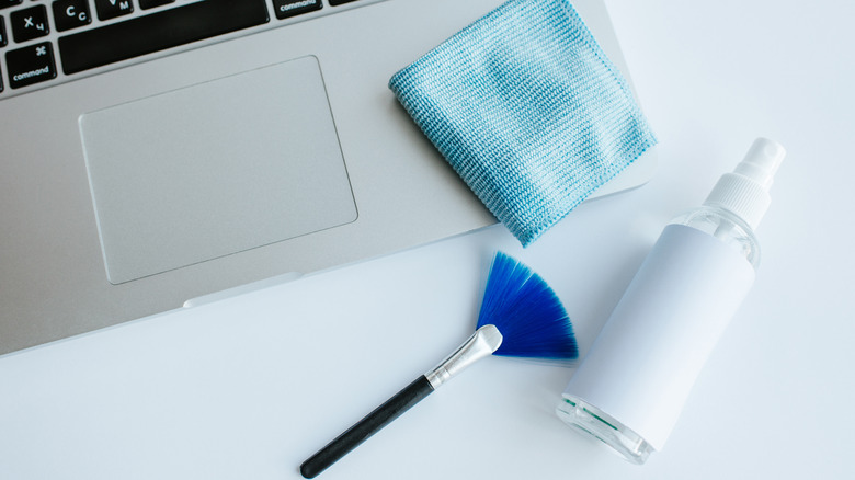 Cleaning supplies next to a laptop.