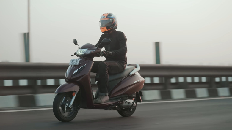 A Honda Activa on a highway, front 3/4 view, burgundy body panels