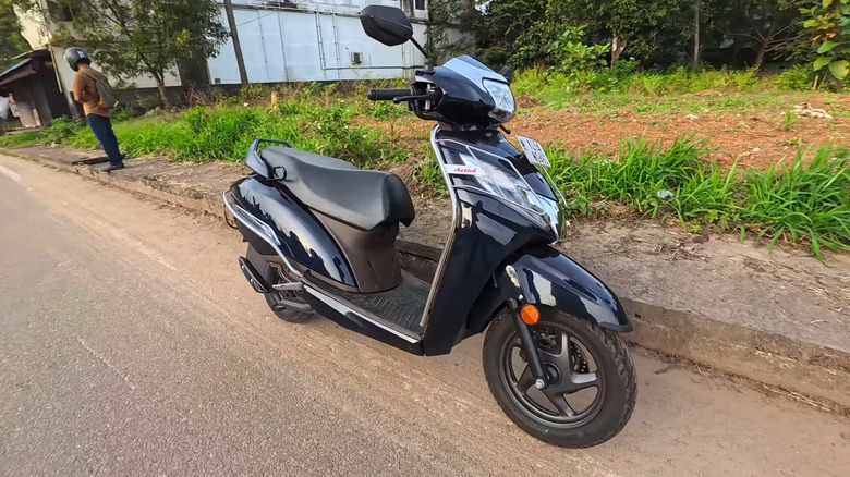 Front 3/4 view of a black Honda Activa in a suburban area of India