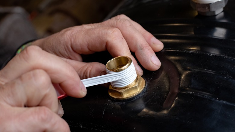 Hands wrapping plumber's tape around the tube threads.