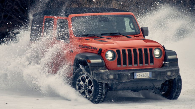 Red colored Jeep Wrangler playing in snow