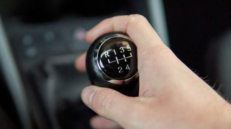 A person's hand on a manual transmission shifter