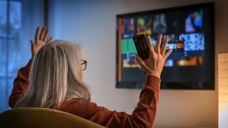 women sitting on a couch holding a remote frustrated with her smart TV