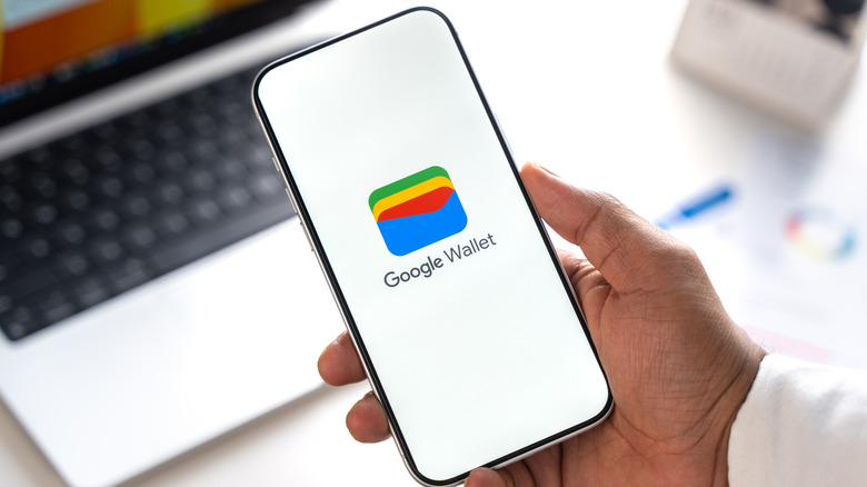 Close-up of hand holding phone with Google Wallet screen on display.