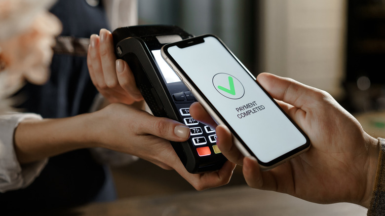 Close-up of hands holding phone making payment with digital wallet.