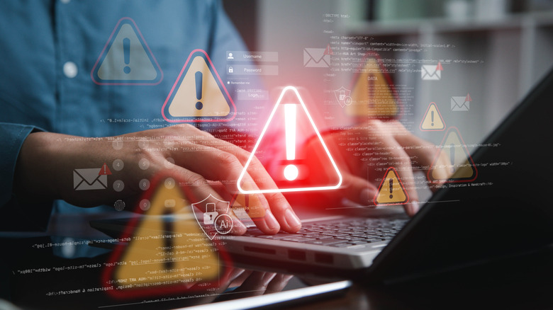 Person typing on laptop with digital overlay of security alert symbols