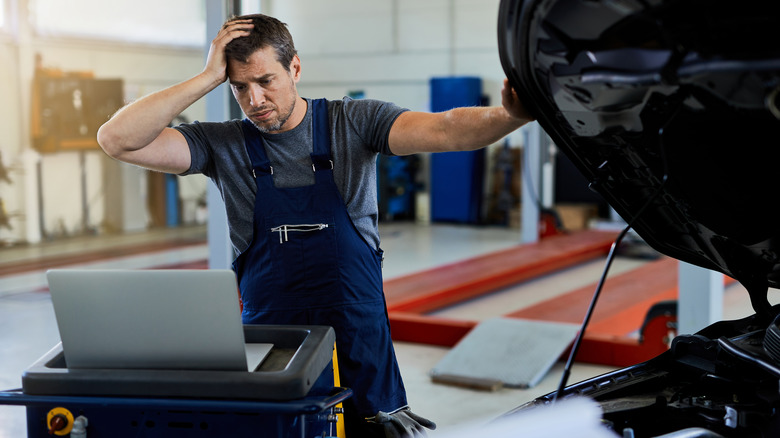 Confused mechanic reads off laptop