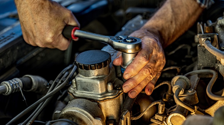 Man uses wrench in engine bay