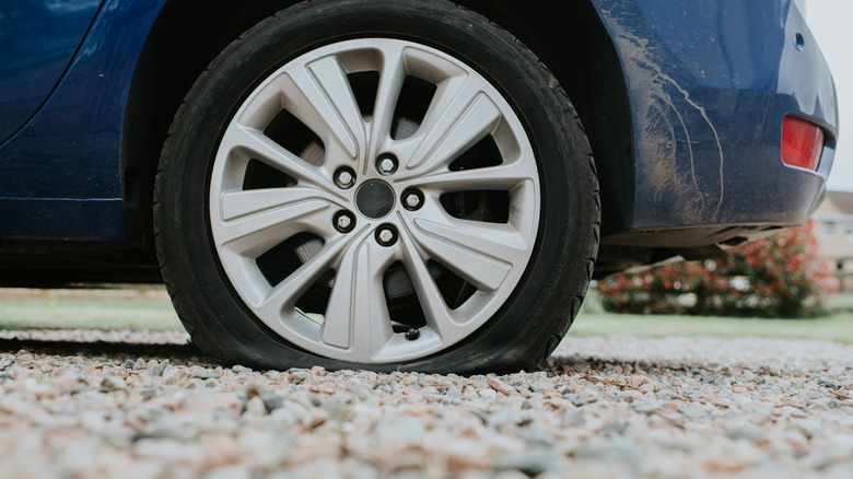 car with a punctured tire on gravel
