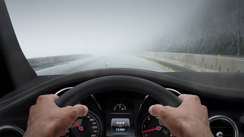 hands gripping steering wheel in front of foggy car windshield