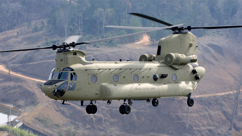 CH-47 flying over dirt and forest