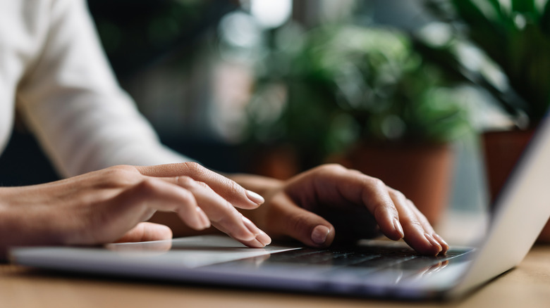 close-up of a person typing on laptop