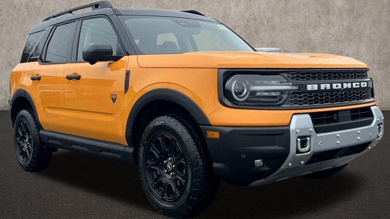 An orange Bronco Sport parked next to a gray building.