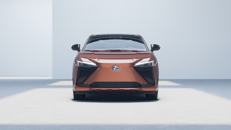 A copper Lexus RZ on a white showroom floor