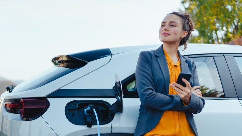 Person leans against their electric car