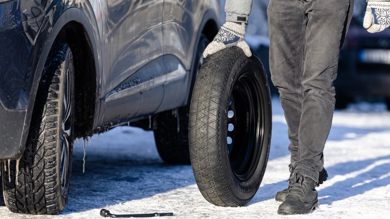 Person rolling donut towards tire that needs to be changed
