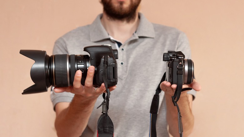 Man holding a DSLR and a Mirrorless Camera 