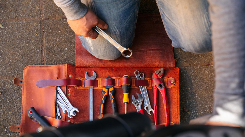 Person handling toolkit for motorcycle maintenance.