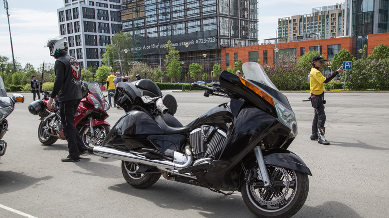 Large touring motorcycle parked in parking lot with rider nearby.