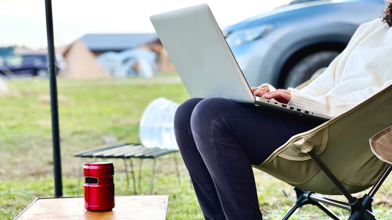 person using laptop camping chair
