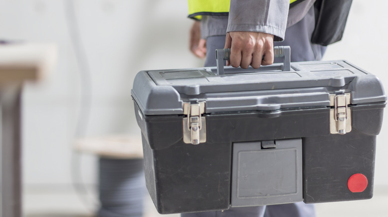 Worker cayrring a dusty toolbox