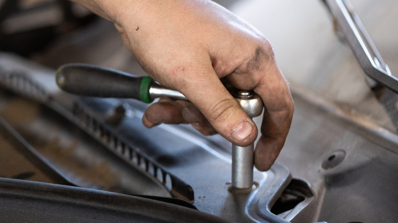A person using a socket wrench on a car.