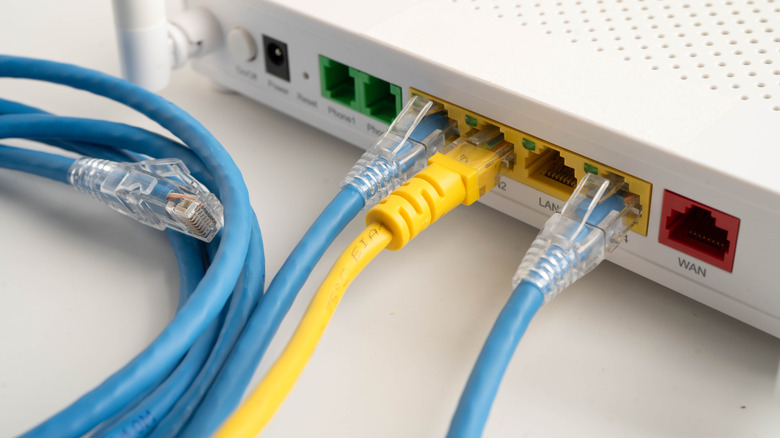 Back of a home internet router with three Ethernet cables attached/