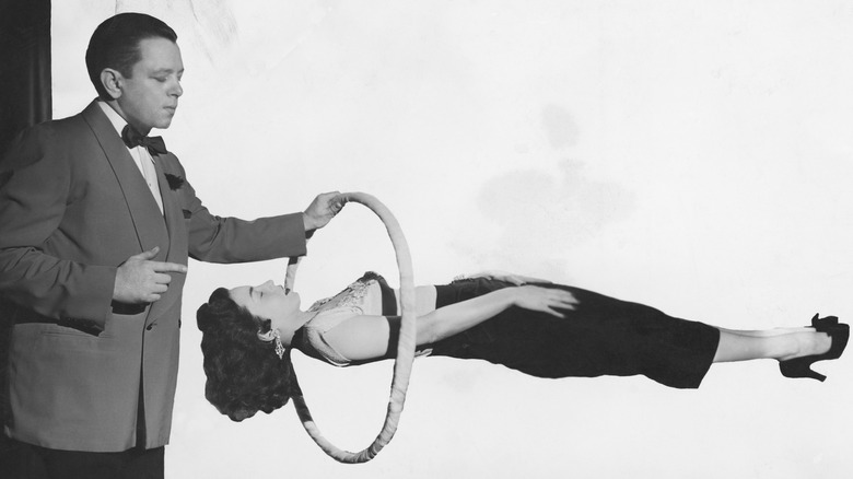 Black and white photo of a magician's levitation trick