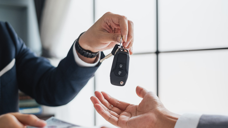 Closeup of hand holding car keys and money