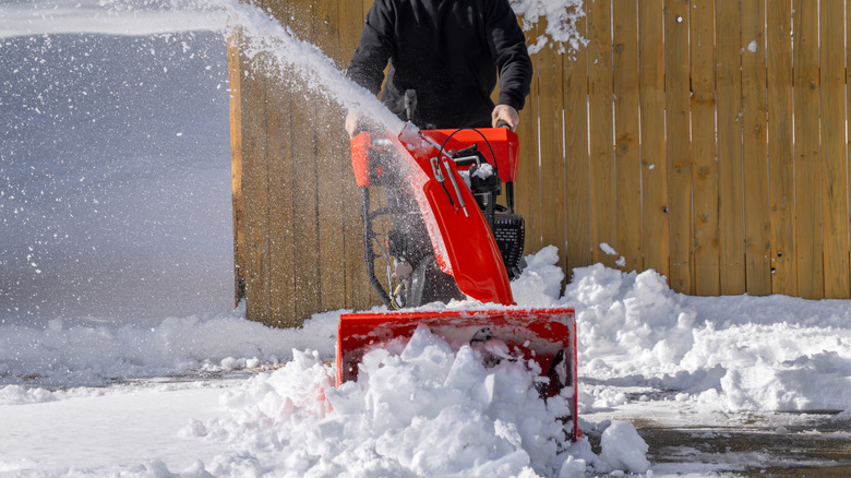 Person removing snow from driveway with snow blower.