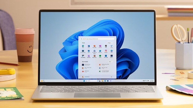 Laptop on table showing Windows 11 with Start menu opened