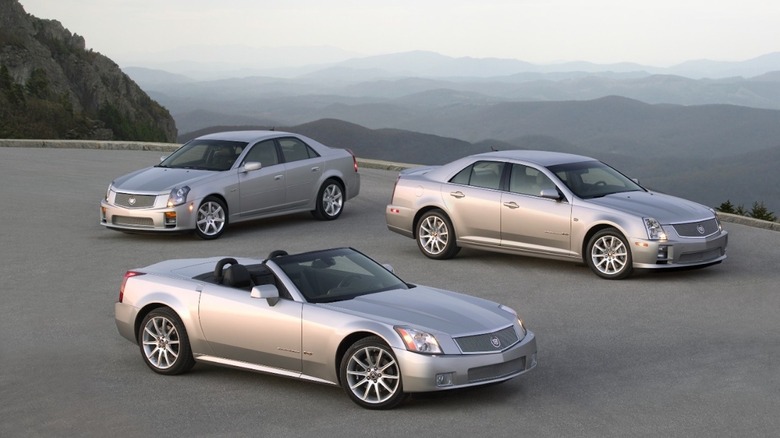 2004 Cadillac V-Series cars with mountainous terrain in the distance.