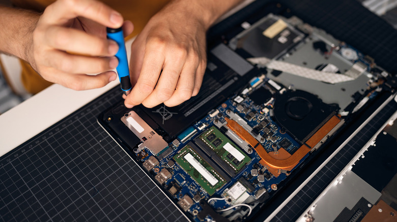 unscrewing internal components form a laptop's motherboard