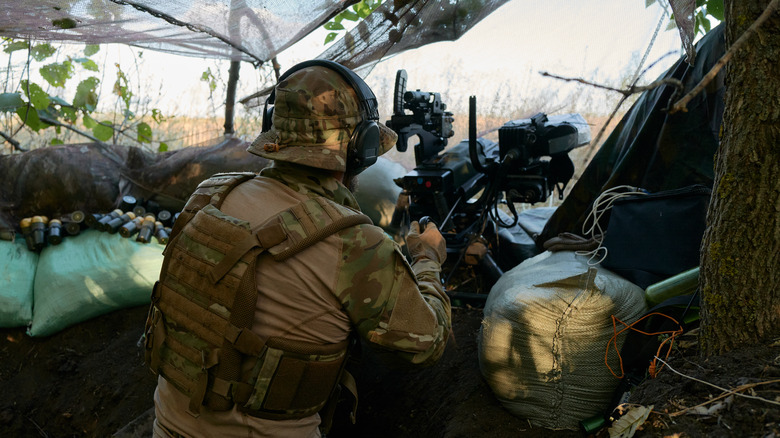 Ukrainian soldier fires grenades from a trench in frontline towards Donetsk