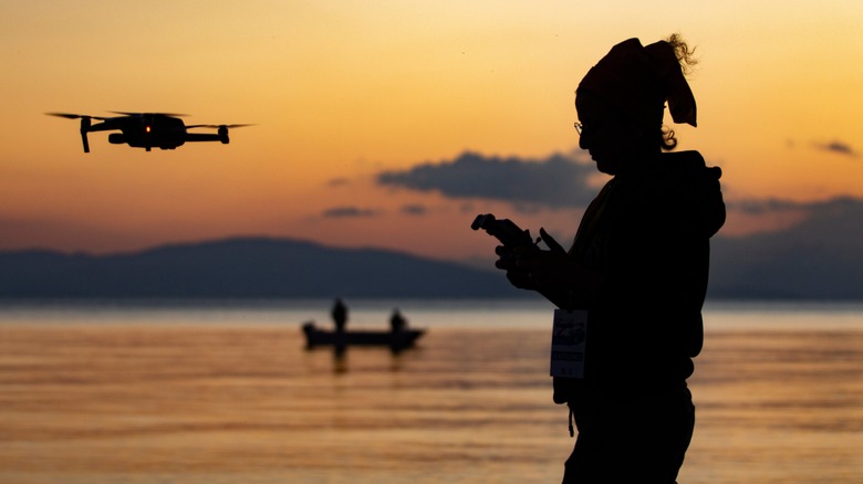 Woman flies drone lake sunset