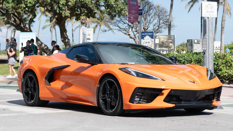 Front 3/4 view of orange C8 Chevy Corvette driving on street.