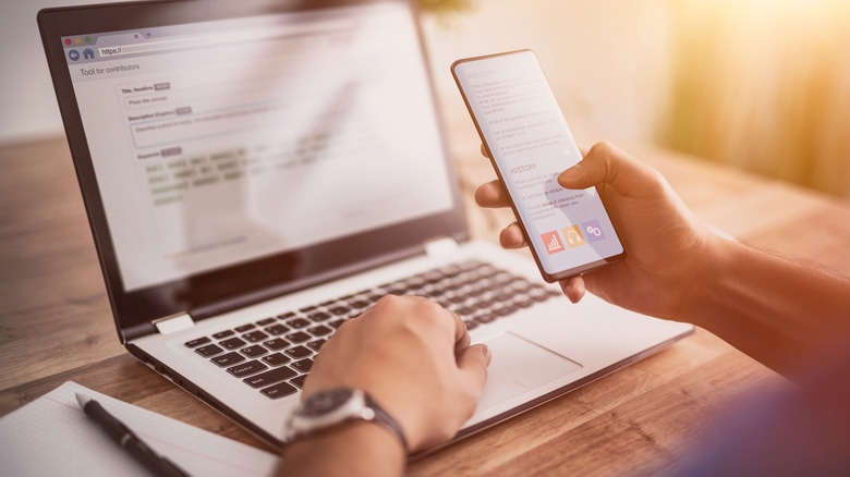 person using phone and laptop simultaneously