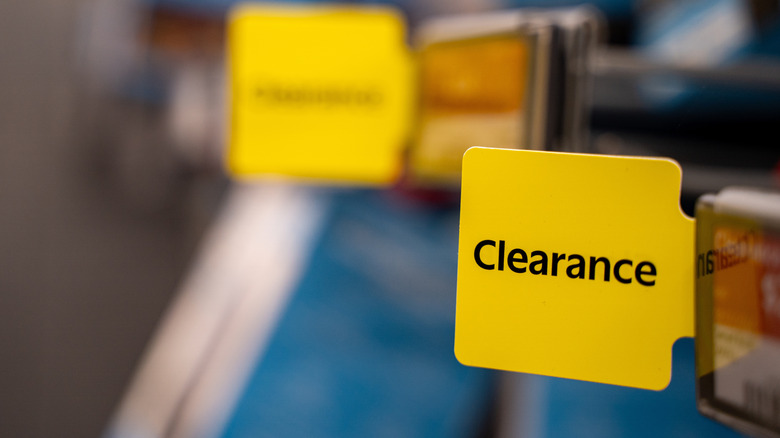 A yellow clearance tag on a shelf with another blurry tag in the background