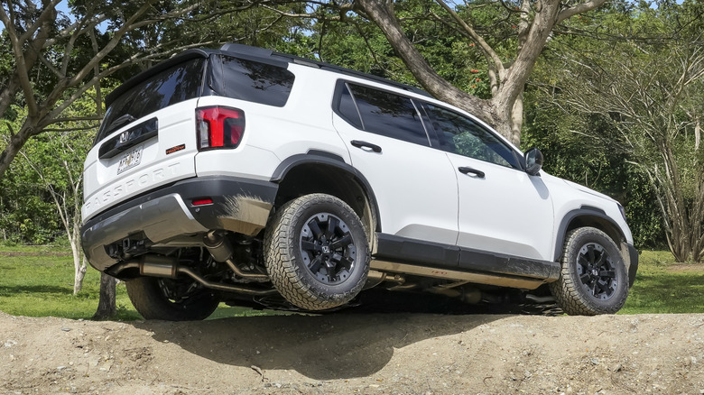 Rear 3/4 view of Honda Passport traversing an off-road trail on three wheels
