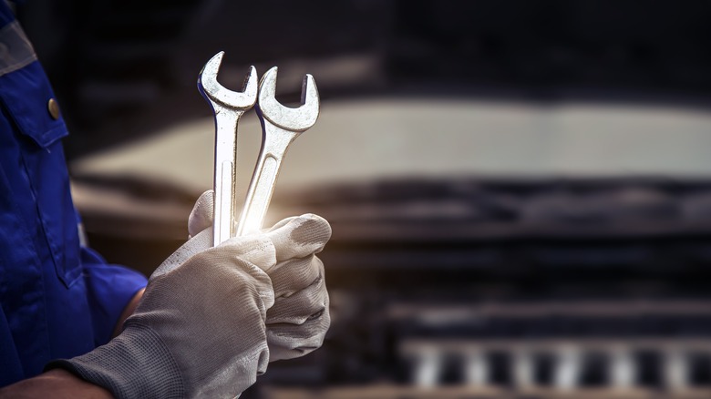 Person holding wrenches servicing car