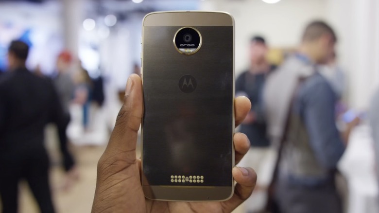 Hand holding a Moto Z with out-of-focus people in the background