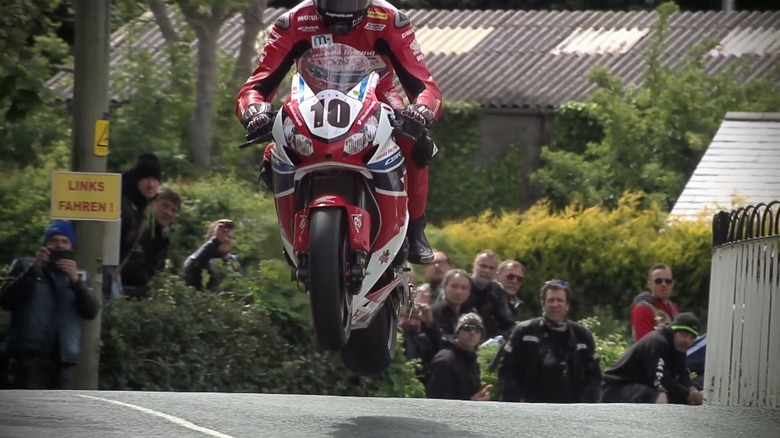 An Isle of Man TT rider catching air over a hill