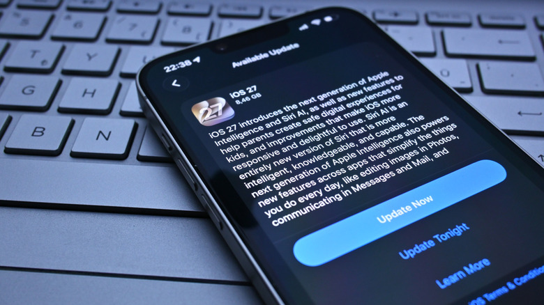 A picture of an iPhone on a laptop keyboard, showing the iOS 27 update screen