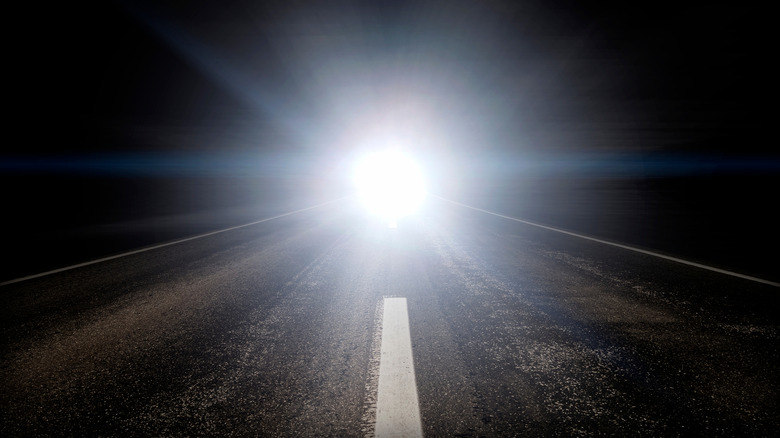A car driving with bright headlights turned on.