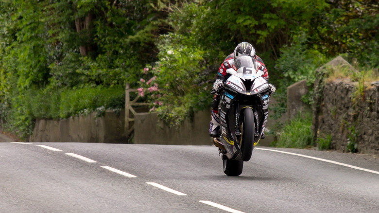 Rider performing wheelie over crest on Isle of Man TT course